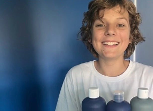 A teenage boy holding three MANLY bottles