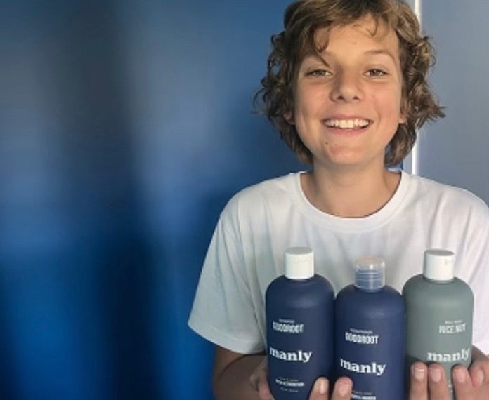 A teenage boy holding three MANLY bottles